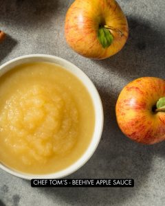 Homemade Apple sauce in a bowl next to some ripe apples.